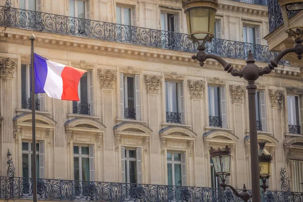 French flag winding, street light and parisian architecture in Paris, France