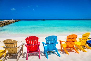 Idyllic beach with rustic wooden adirondack chairs in Aruba, Dutch Antilles clipart