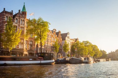 Amsterdam canal with houseboats and dutch architecture at sunrise, Netherlands