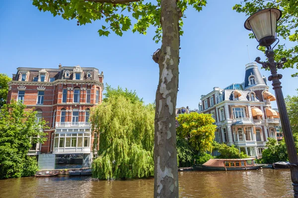 Amsterdam canal with houseboats and dutch architecture at sunrise, Netherlands