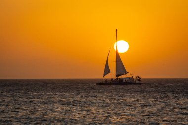 Idyllic caribbean beach with sailboat in Aruba at golden sunset, Dutch Antilles