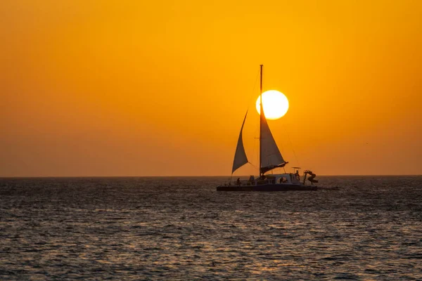 Idyllic caribbean beach with sailboat in Aruba at golden sunset, Dutch Antilles