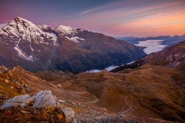 Grossglockner 'ın yukarısındaki puslu vadi ve dağ manzarası dramatik şafakta, Avusturya alp.