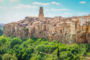 Pitigliano duvarı ve tepelerin üzerindeki şehir manzarası ve yeşil selvi, Toskana, İtalya