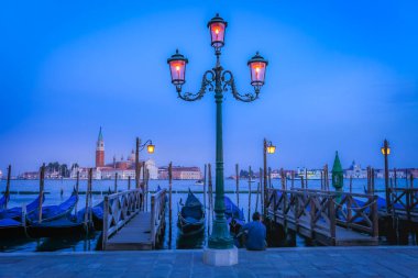 Gondole, Büyük Kanal 'da ahşap demirleme direkleriyle kenetlendi ve akşam San Giorgio Maggiore Kilisesi, Ethereal Venice, İtalya