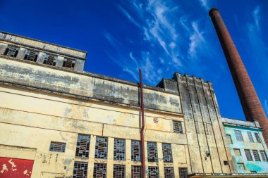 Güneşli bir günde tuğla bacalı terk edilmiş ve çürümüş bir fabrika.