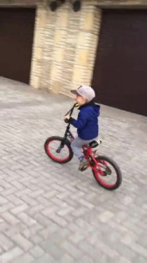 POV sevimli küçük oğlan 4-5 yaşlarında, bebek çocuk güneşli yaz gününde bisiklete biniyor, çocuk parkta oynuyor ve bisiklete biniyor, çocuk konseptiyle bisiklete biniyor. Dikey video hikayeleri.