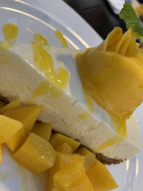 Beyaz tabakta mango peynirli kek.