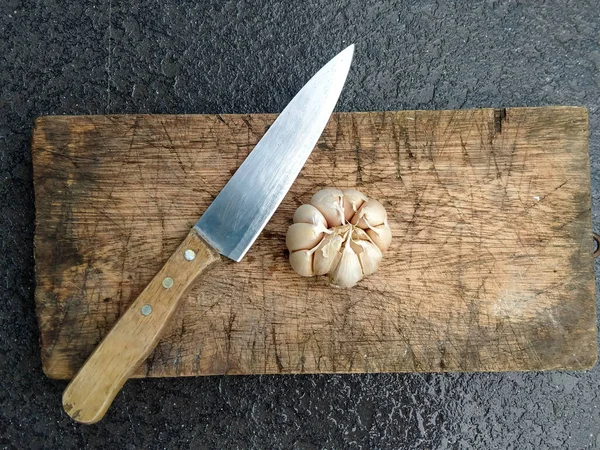 Sarımsak ve bıçak ahşap kesim tahtasının üstünde.