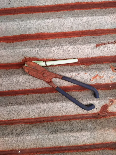 Paslı çinko makas ve eski çinko çatıda bir kalem.