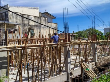 Bir işçi, bir ev inşa etmek için bambunun üzerinde oturuyor..