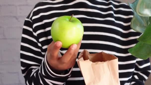 kéz gazdaság zöld alma és gazdaság egy papír bevásárló táska
