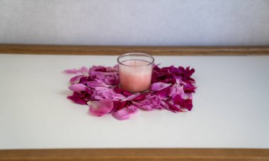 Güzel pembe ve mor çiçek yaprakları üzerinde pembe mum, ürün yerleştirme 