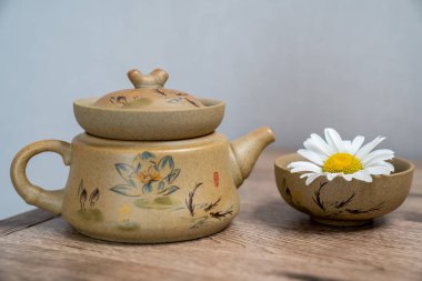 Seramik çay demliği. Tahta bir masada çiçekli.