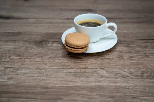 cup of coffee espresso in white cup and macaroons on wooden background