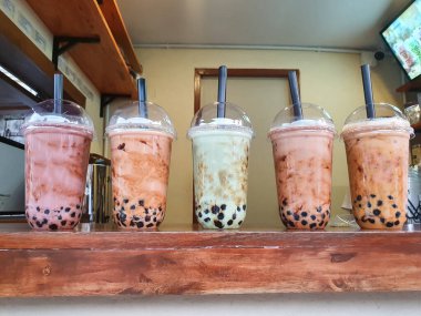 iced asian bubble milk tea in a plastic glass cup with a straw on a wooden table