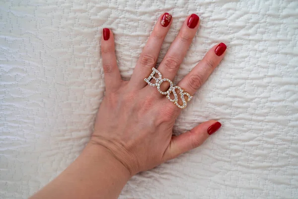 close-up of a female hand palm with a red manicure, ring boss