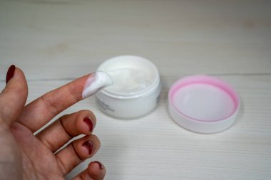 Kozmetik krem süren kadın, yüz kremi kavanozunun yanında beyaz bakım kremi olan el, kişisel bakım konsepti.