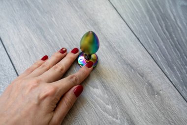 woman hand with manicure holding bright shiny butt anal plug