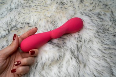 woman hand with manicure holding pink vibrator rabbit, couple games 
