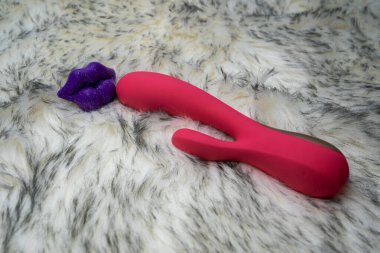 pink vibrator rabbit and lips, concept of woman pleasure, game in bed