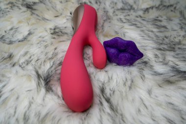 pink vibrator rabbit and lips, concept of woman pleasure, game in bed