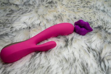 pink vibrator rabbit and lips, concept of woman pleasure, game in bed
