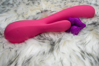 pink vibrator rabbit and lips, concept of woman pleasure, game in bed