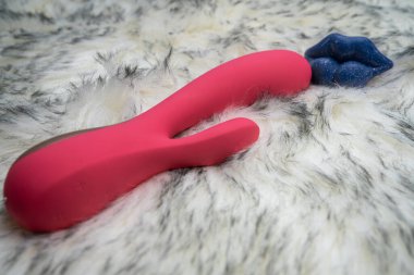 pink vibrator rabbit and lips, concept of woman pleasure, game in bed