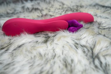 pink vibrator rabbit and lips, concept of woman pleasure, game in bed