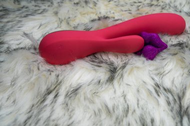 pink vibrator rabbit and lips, concept of woman pleasure, game in bed