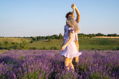 romantic couple in purple matching outfit in love dancing together in lavender field