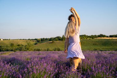 romantic couple in purple matching outfit in love dancing together in lavender field