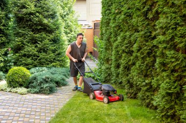 handsome man is cutting the lawn, process to cut the grass at the yard with special machine lawn mover, green garden