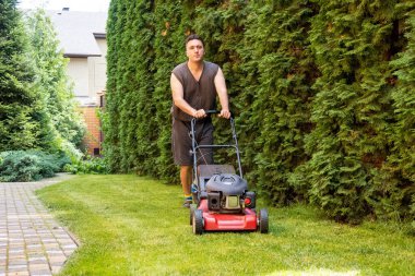 handsome man is cutting the lawn, process to cut the grass at the yard with special machine lawn mover, green garden