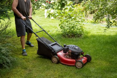 handsome man is cutting the lawn, process to cut the grass at the yard with special machine lawn mover, green garden