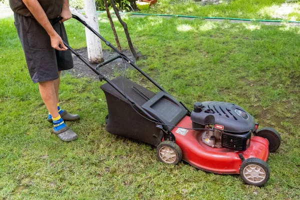 handsome man is cutting the lawn, process to cut the grass at the yard with special machine lawn mover, green garden