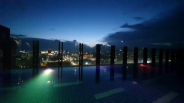 pool with lightings illumination at dusk night, view on the city from above, rooftop pool  