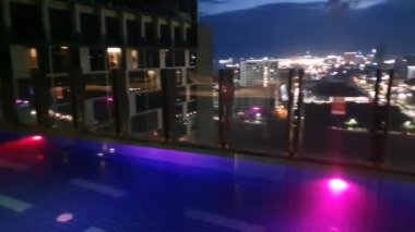 pool with lightings illumination at dusk night, view on the city from above, rooftop pool  