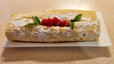 homemade baked cake with cherry and mint on the plate on the kitchen table 