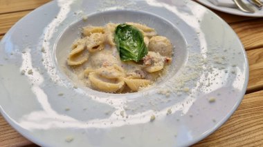 pasta with cheese and vegetables on a white plate at restaurant, eating out, way of serving food 