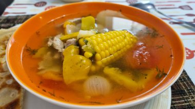 corn soup with vegetables and spices on a wooden table next to bread at kitchen 