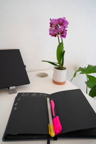 workplace, cozy workspace, office desk with laptop, notebook to do list, pen and orchid flowers, working atmosphere