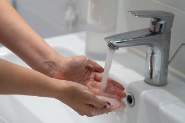 close up woman washing hands with soap and water, white foam, in the bathroom, under tap in the sink, personal hygiene and care, coronavirus prevention