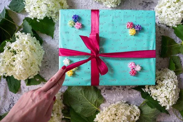 hydrangea flower, green turquoise color gift box with red ribbon bow on grey wooden background. Concept: holiday, celebration, birthday, New Year, Christmas, Valentines Day, Mothers Day, Thanksgiving