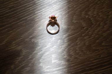 Ahşap bir arka planda nişan yüzüğü, güneş ışığı, gölge ve yansımadan gelen yaratıcı ışık. 