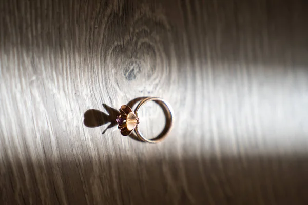 wedding engagement ring on a wooden background, creative light backlight from sunbeam, shadow and reflection