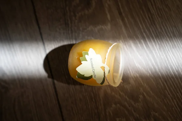 scented candle in a glass cover on a wooden background, sunbeam light creates creative effect of burning candle, therapy, meditation, aromatherapy to relax mindset, relive stress, smells good