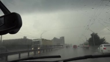 Kötü hava, yağmurlu gün, arabanın ön camına yağmur damlaları, ön cam silecekleri çalışıyor, yağmuru kaldırıyor, yolda çekim yapıyor, sokağa yağmur yağıyor.