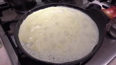 Büyükanne kadın modern mutfaktaki kızartma tavasında ince krepler pişiriyor.